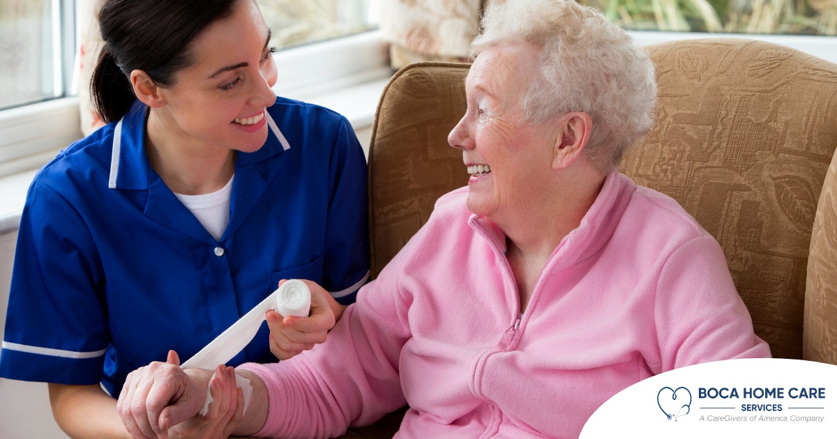 A caregiver demonstrates wound care by wrapping a senior client’s wound.