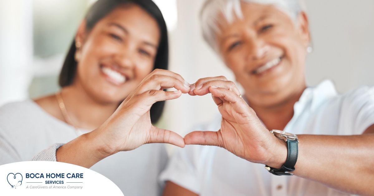 A daughter and an older mother create a heart with their hands, representing the feeling that is highlighted during National Family Caregivers Month