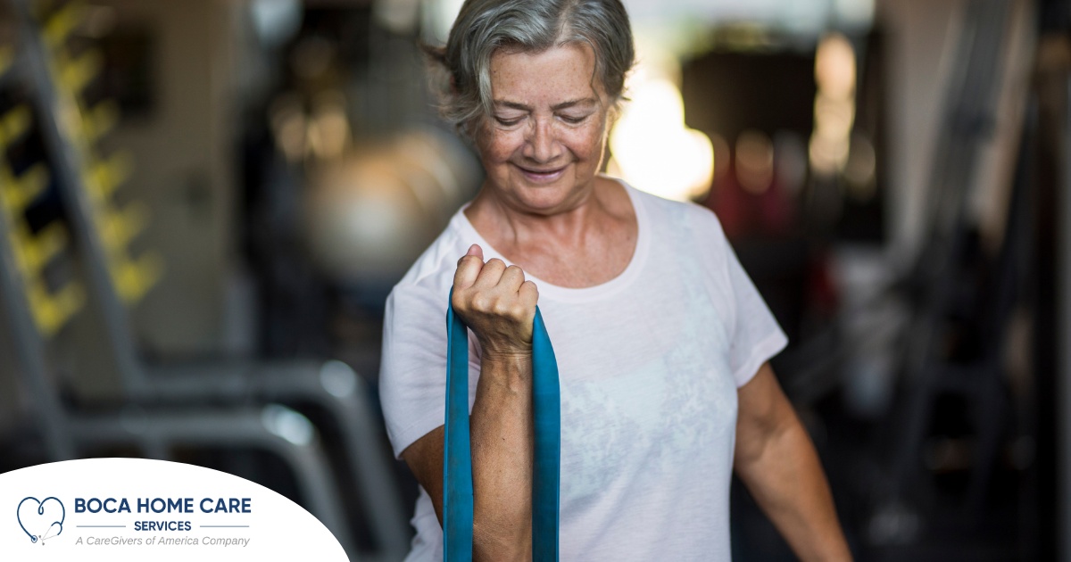 An older woman uses a resistance band to exercise, representing how staying active can help older adults keep their blood pressure in a healthy range.